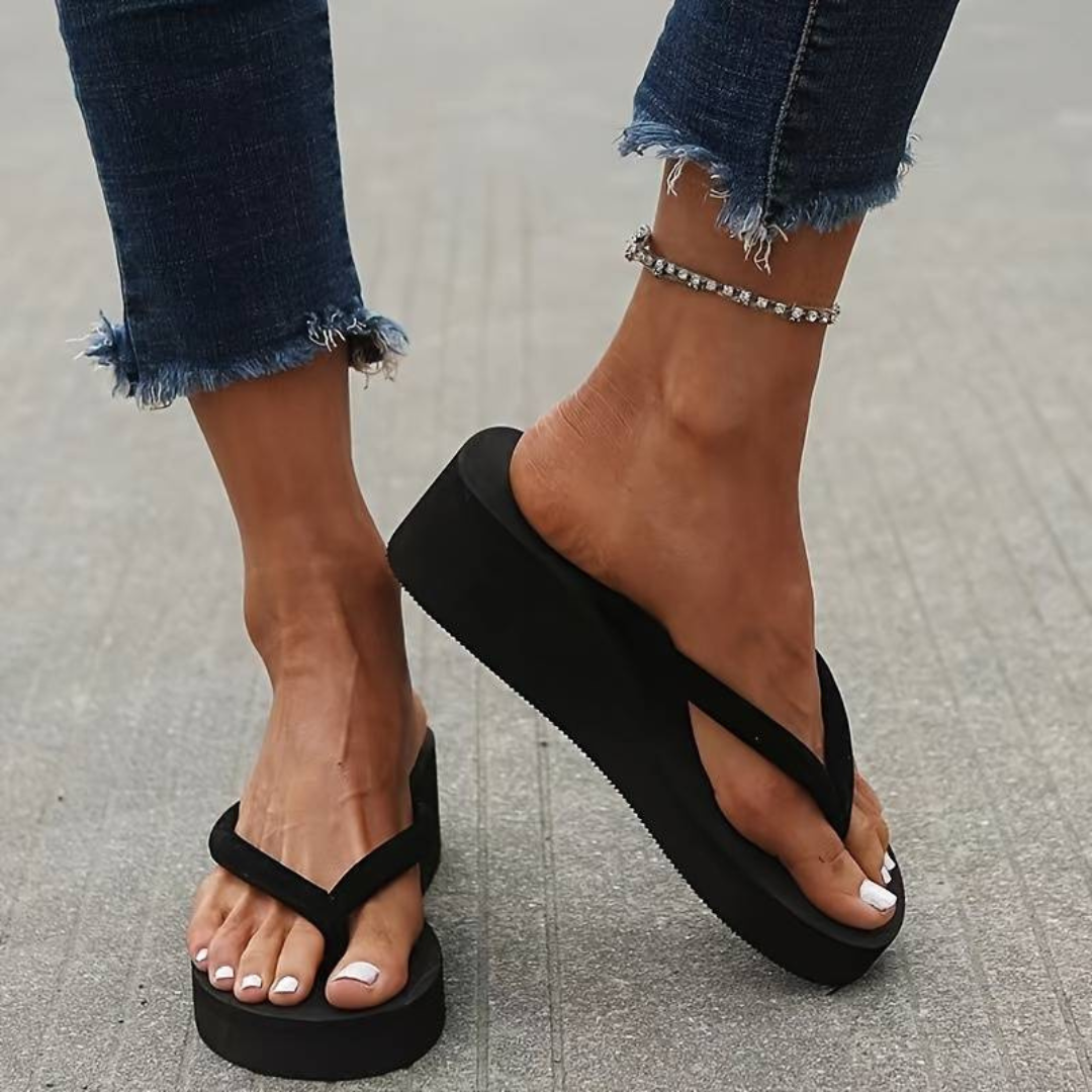 "Tongs femme compensées noires avec talon et semelle coussinée, bride souple, parfaites pour l'été."