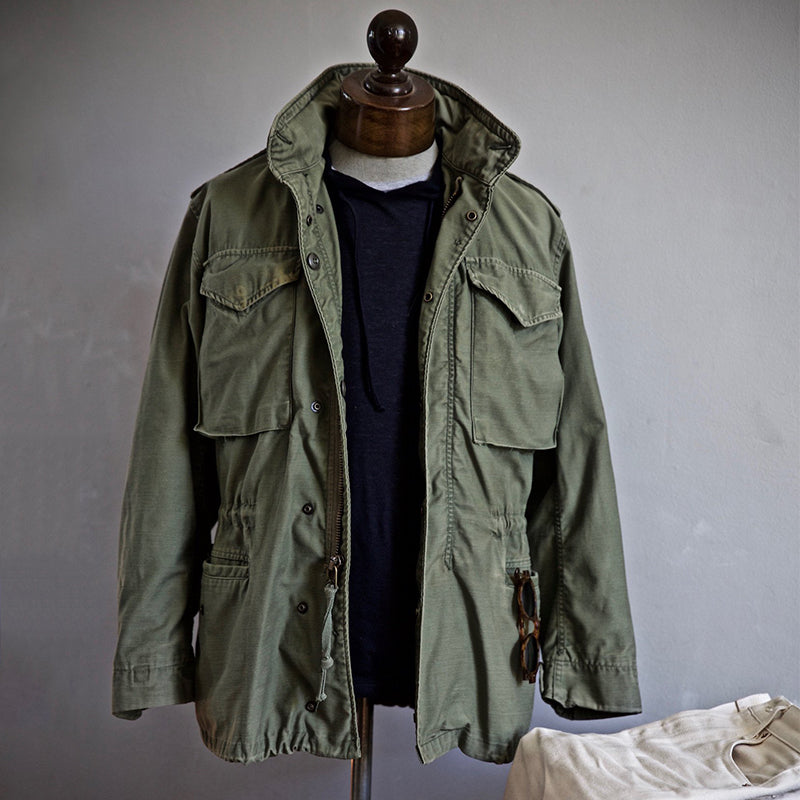 "Veste M-65 militaire verte en nylon, quatre poches, capuche dissimulée, style intemporel et durable pour hommes."