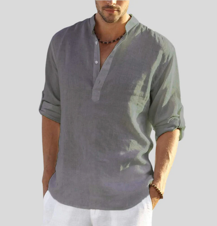 Chemise en lin homme élégante, manches repliées, col boutonné partiel, tissu léger blanc, style décontracté et estival.