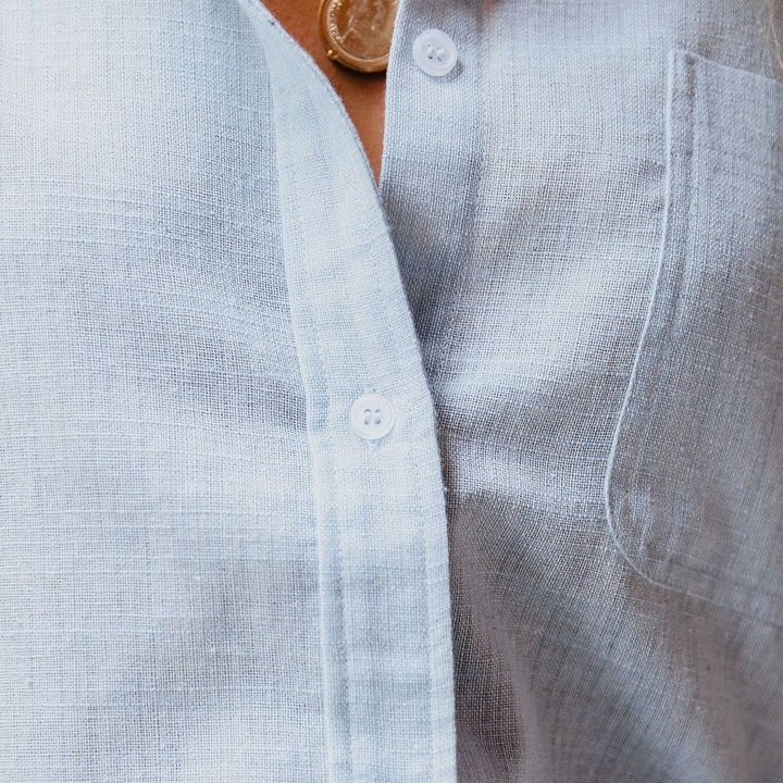 "Chemise femme en lin bleu clair, coupe ample, manches longues, col classique, boutons simples pour élégance décontractée."