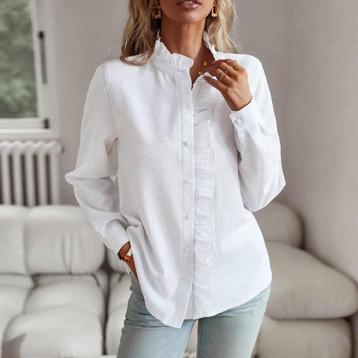 Chemisier femme élégant Lisbeth, col à manchettes distinctif sur fond clair, manches longues et tissu luxueux.