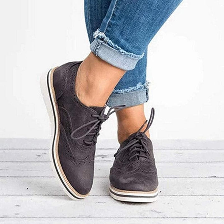 Derby femme en cuir velours, détails brogue, couleur élégante, lacets classiques, idéale pour un style raffiné.