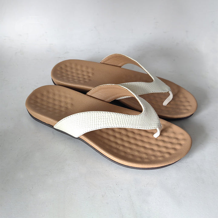 "Des tongs blanches élégantes et légères pour femmes sur fond beige, idéales pour l'été avec une semelle ergonomique."