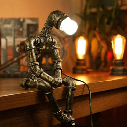Lampe design robot en fer à éclairage ajustable rétro, bras et tête mobiles, finition couleur laiton, style industriel.