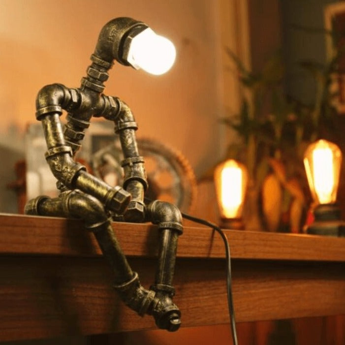 Lampe design robot en fer à éclairage ajustable rétro, bras et tête mobiles, finition couleur laiton, style industriel.