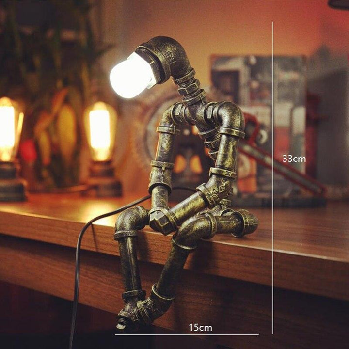 Lampe design robot en fer à éclairage ajustable rétro, bras et tête mobiles, finition couleur laiton, style industriel.