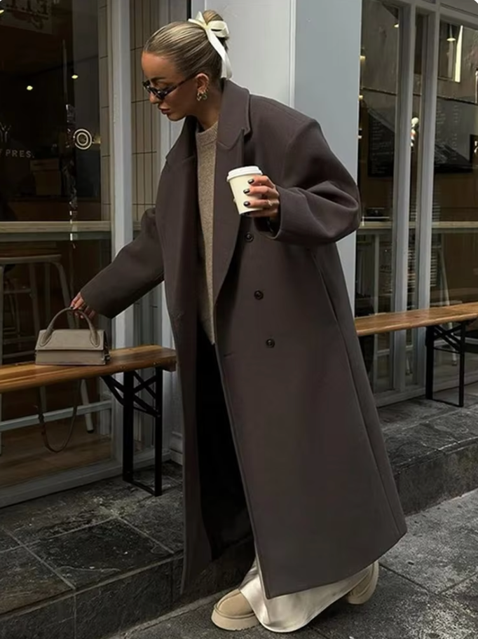 "Manteau long classique femme hiver élégant avec col imposant, coupe ajustée, couleur neutre, idéal saisons froides."