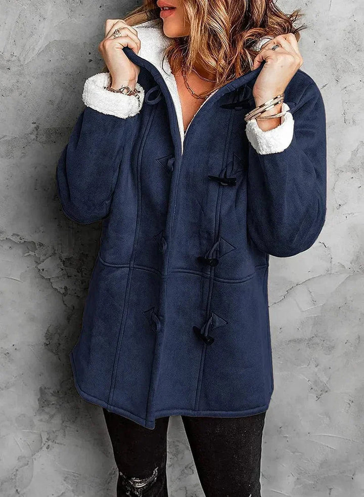 Manteau long en cachemire gris, coupe élégante avec capuche intégrée et boutons en corne, offrant chaleur et douceur.