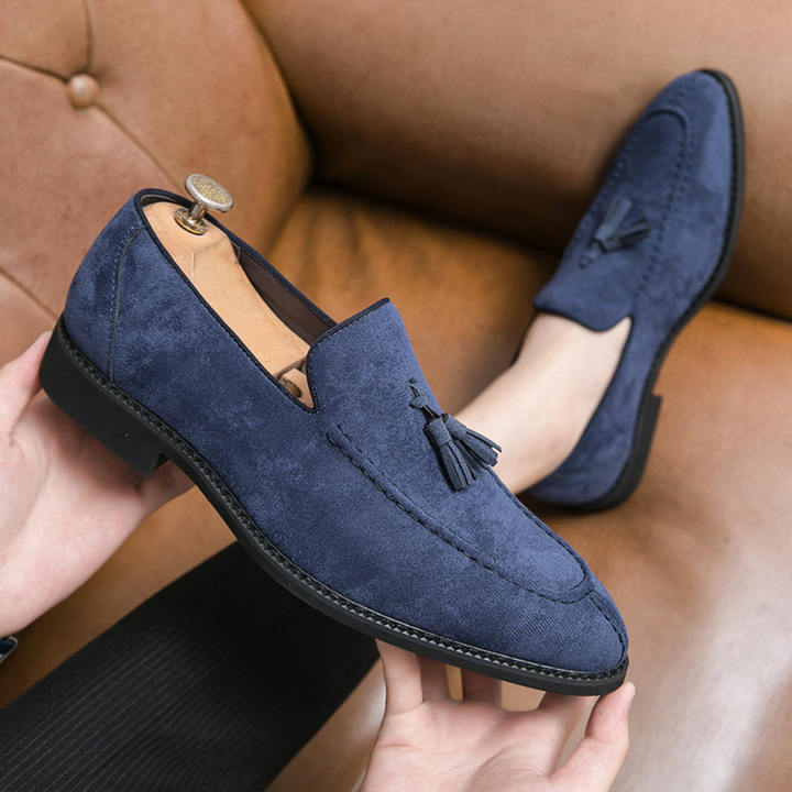 "Mocassins en daim pour homme, vue latérale, couleur marron avec pampilles élégantes, semelle caoutchouc, style raffiné."