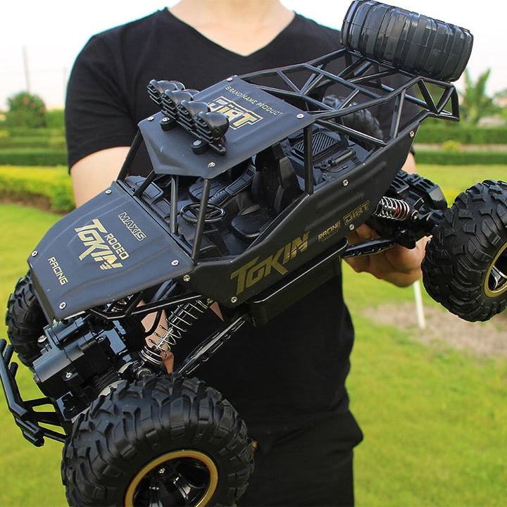"Monster Truck RC 4x4 rouge sur terrain rocailleux, suspension robuste et pneus antidérapants pour aventures extrêmes."