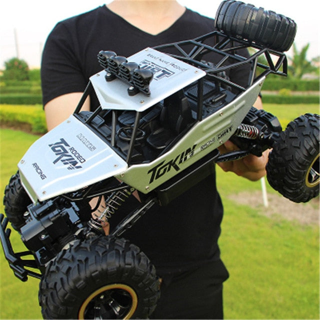 "Monster Truck RC 4x4 rouge sur terrain rocailleux, suspension robuste et pneus antidérapants pour aventures extrêmes."