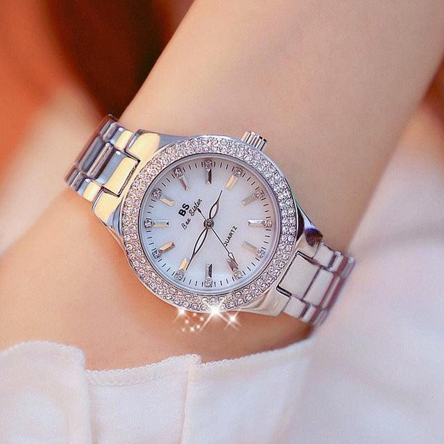 "Montre femme élégante avec strass scintillants et bracelet métallique argenté or doré, cadran rond lumineux."