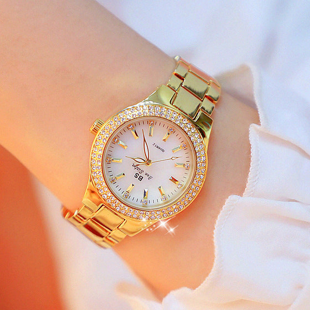 "Montre femme élégante avec strass scintillants et bracelet métallique argenté or doré, cadran rond lumineux."