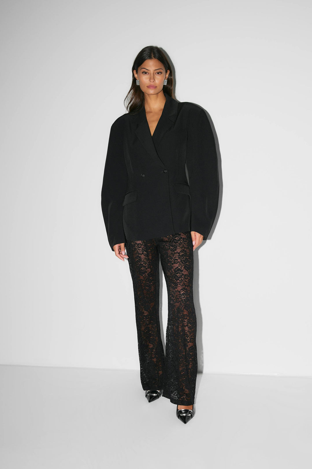 Pantalon évasé à taille haute en dentelle noire, silhouette élancée, matière florale transparente pour allure glamour.
