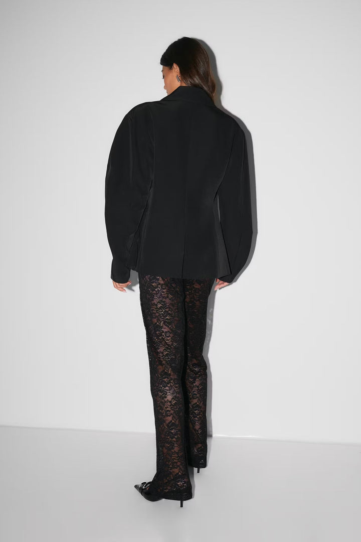 Pantalon évasé à taille haute en dentelle noire, silhouette élancée, matière florale transparente pour allure glamour.