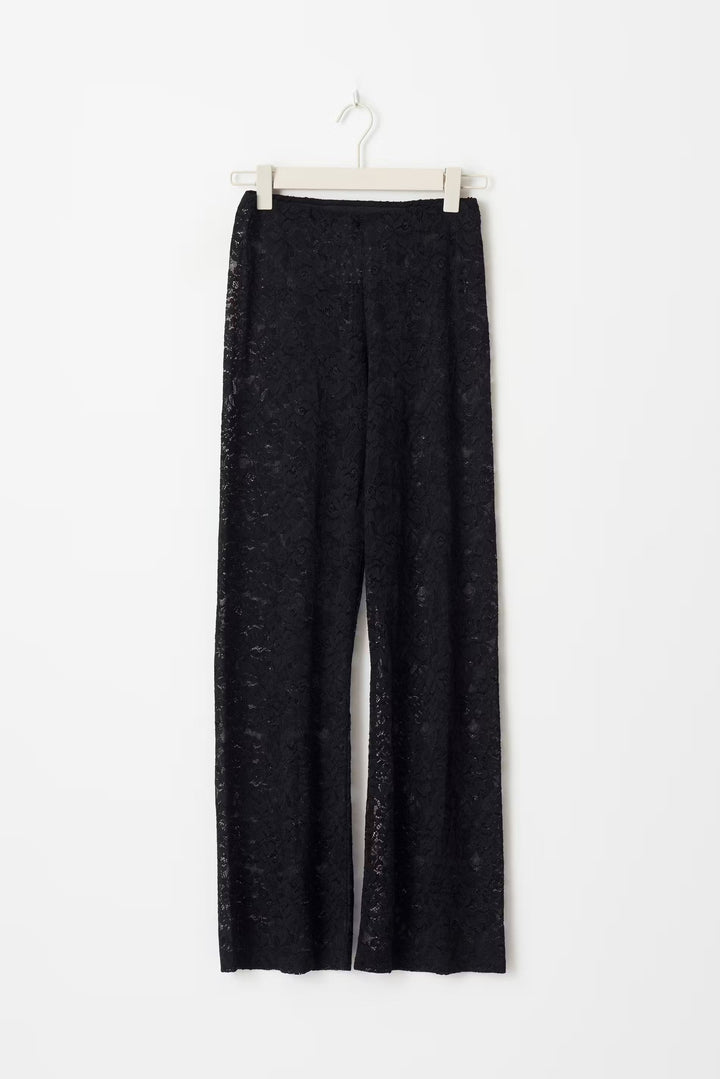 Pantalon évasé à taille haute en dentelle noire, silhouette élancée, matière florale transparente pour allure glamour.