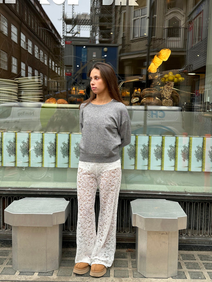 Pantalon évasé à taille haute en dentelle noire, silhouette élancée, matière florale transparente pour allure glamour.