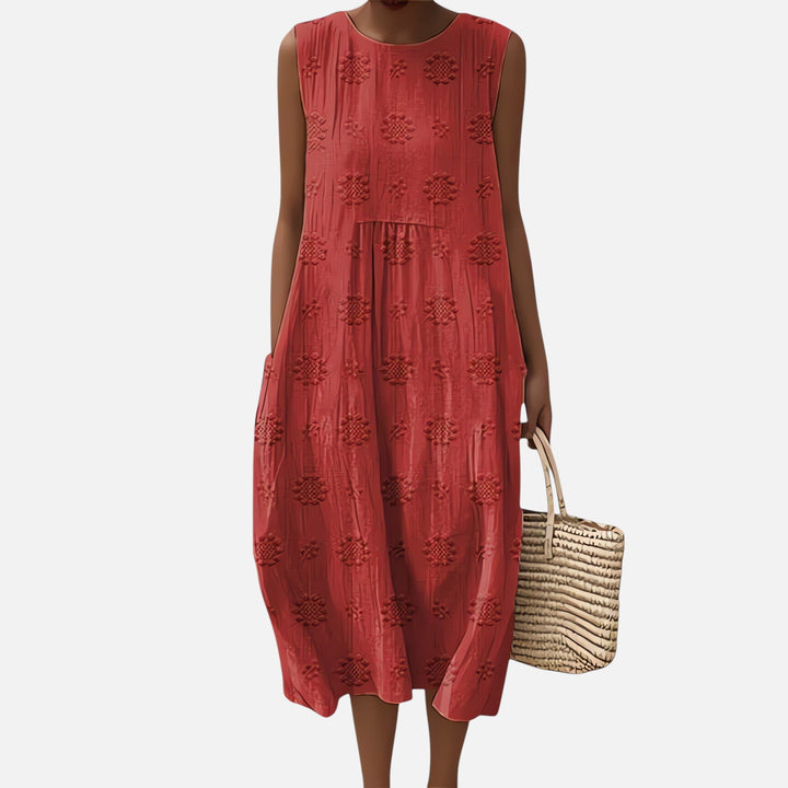 "Robe bohème élégante en coton, mi-longue sans manches, coupe fluide, avec poches, motif géométrique, style estival chic."