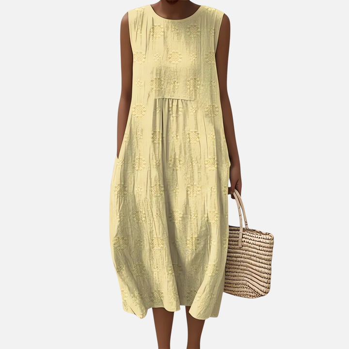 "Robe bohème élégante en coton, mi-longue sans manches, coupe fluide, avec poches, motif géométrique, style estival chic."