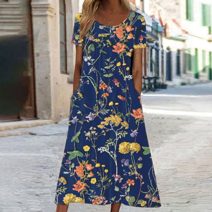 "Robe d'été fluide avec motifs floraux turquoise et blancs, coupe bohème chic, manches courtes, idéale pour l'été."