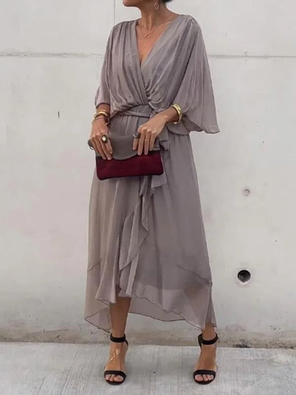 "Robe en mousseline de soie bleue avec col en V et manches 3/4, coupe fluide pour occasions élégantes."