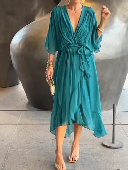 "Robe en mousseline de soie bleue avec col en V et manches 3/4, coupe fluide pour occasions élégantes."