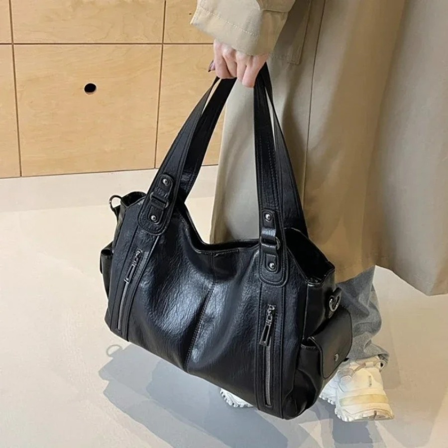 "Sac Amber en cuir végétal marron avec bandoulière, détails métalliques et poches, design élégant et spacieux pour femme."