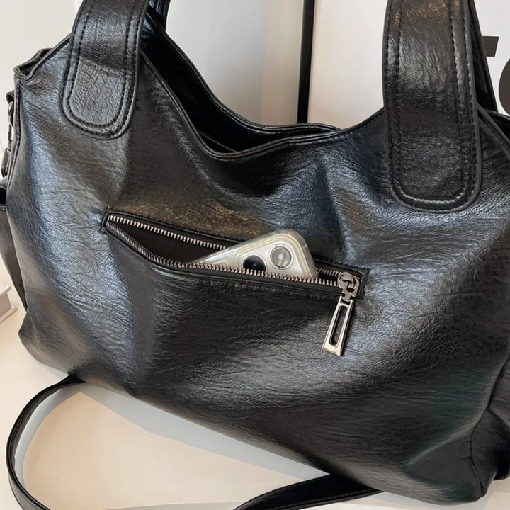 "Sac Amber en cuir végétal marron avec bandoulière, détails métalliques et poches, design élégant et spacieux pour femme."