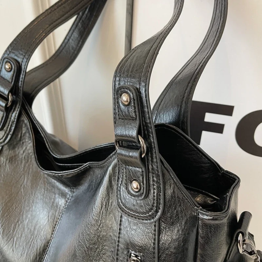 "Sac Amber en cuir végétal marron avec bandoulière, détails métalliques et poches, design élégant et spacieux pour femme."