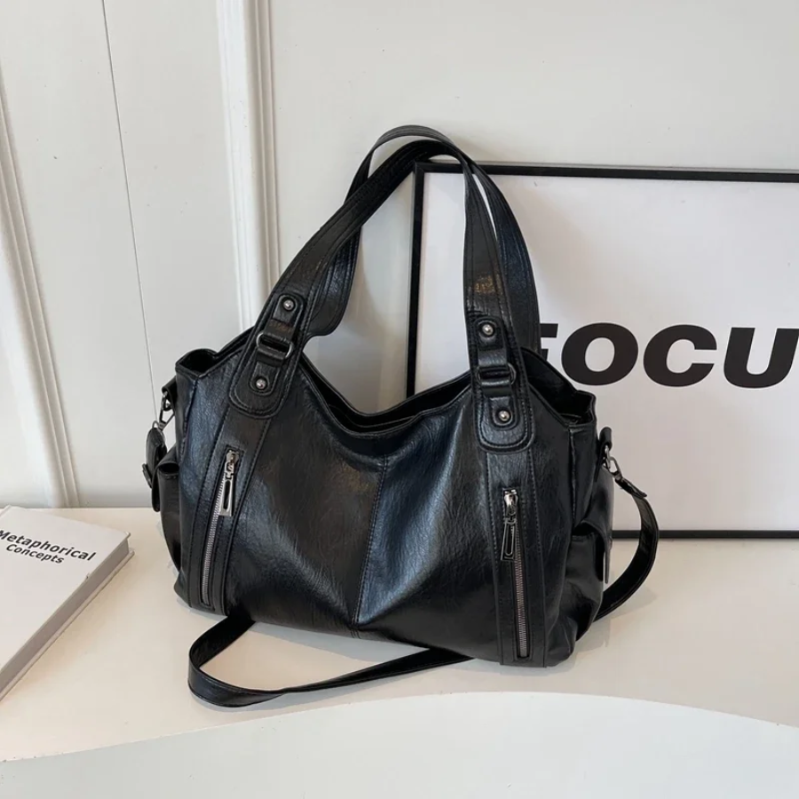 "Sac Amber en cuir végétal marron avec bandoulière, détails métalliques et poches, design élégant et spacieux pour femme."