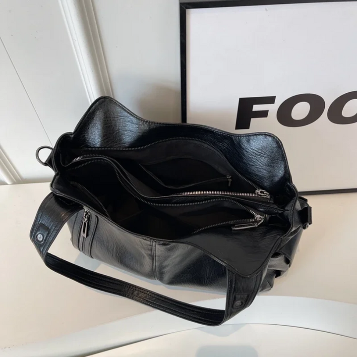 "Sac Amber en cuir végétal marron avec bandoulière, détails métalliques et poches, design élégant et spacieux pour femme."