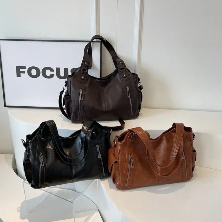 "Sac Amber en cuir végétal marron avec bandoulière, détails métalliques et poches, design élégant et spacieux pour femme."