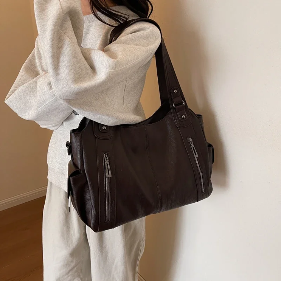 "Sac Amber en cuir végétal marron avec bandoulière, détails métalliques et poches, design élégant et spacieux pour femme."