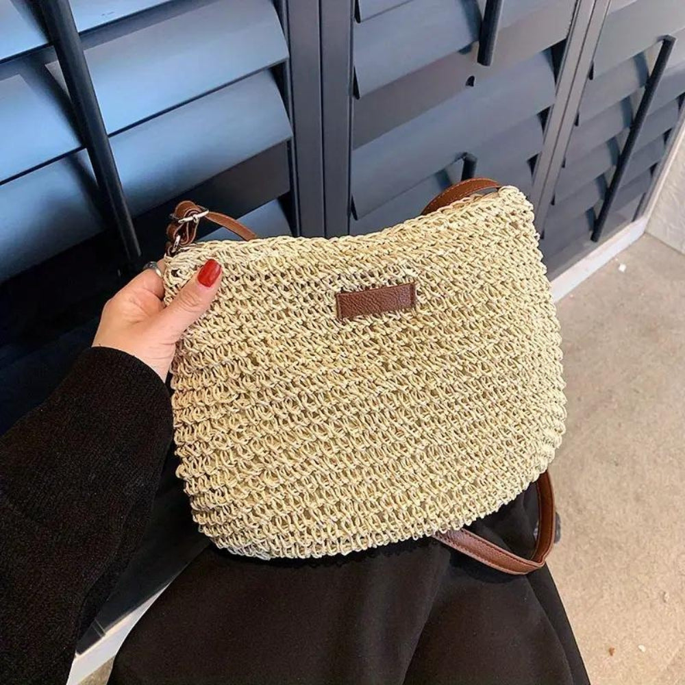 "Sac bandoulière Léandre en paille premium avec finitions cuir végan, bandoulière ajustable et fermeture éclair sécurisée."