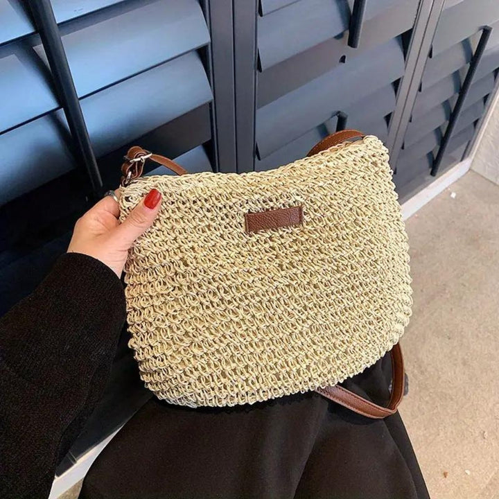 "Sac bandoulière Léandre en paille premium avec finitions cuir végan, bandoulière ajustable et fermeture éclair sécurisée."