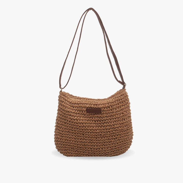 "Sac bandoulière Léandre en paille premium avec finitions cuir végan, bandoulière ajustable et fermeture éclair sécurisée."