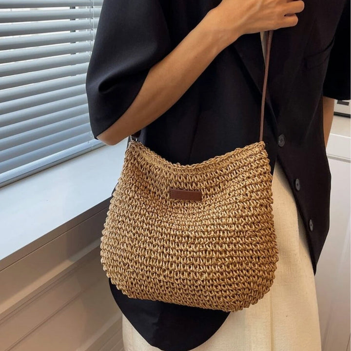 "Sac bandoulière Léandre en paille premium avec finitions cuir végan, bandoulière ajustable et fermeture éclair sécurisée."