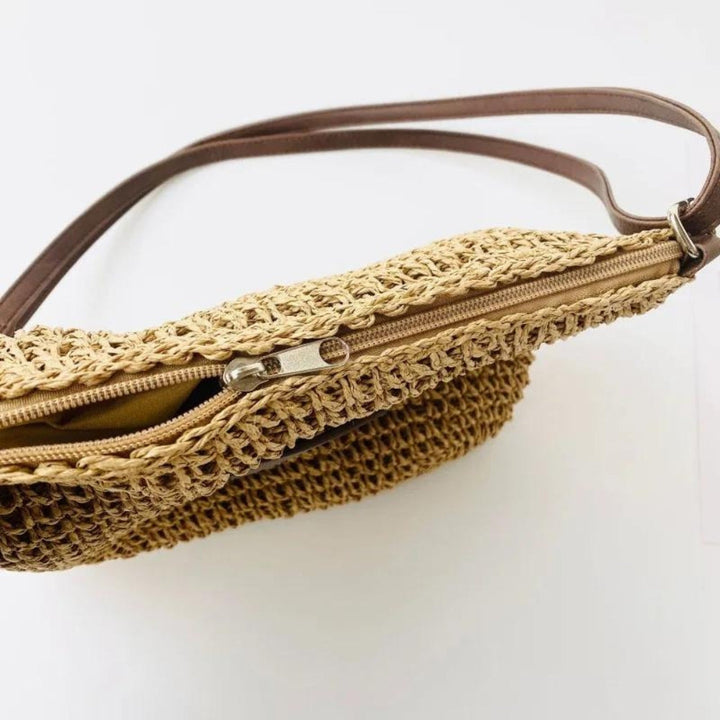 "Sac bandoulière Léandre en paille premium avec finitions cuir végan, bandoulière ajustable et fermeture éclair sécurisée."
