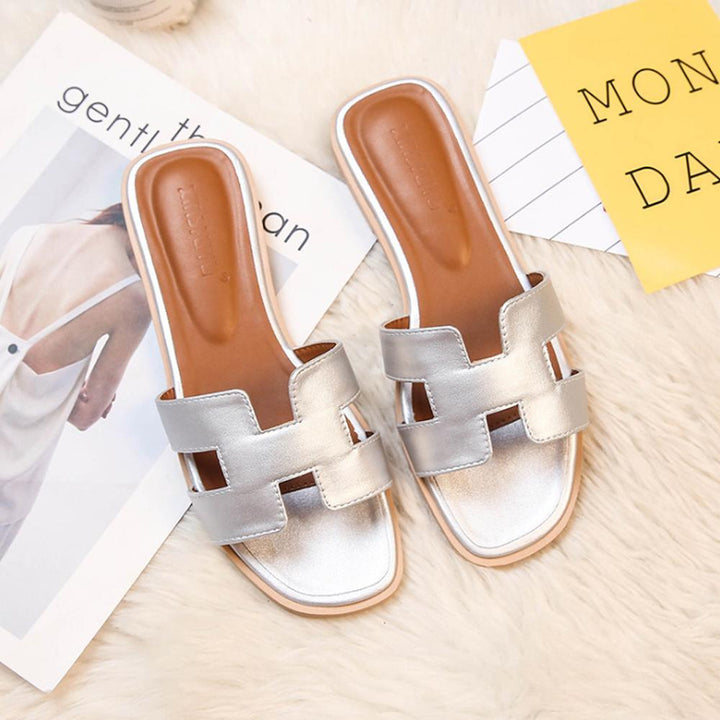 Sandales H-Stylé pour femmes en cuir, design moderne en H, talon plat, couleur beige, élégance et confort pour l'été.