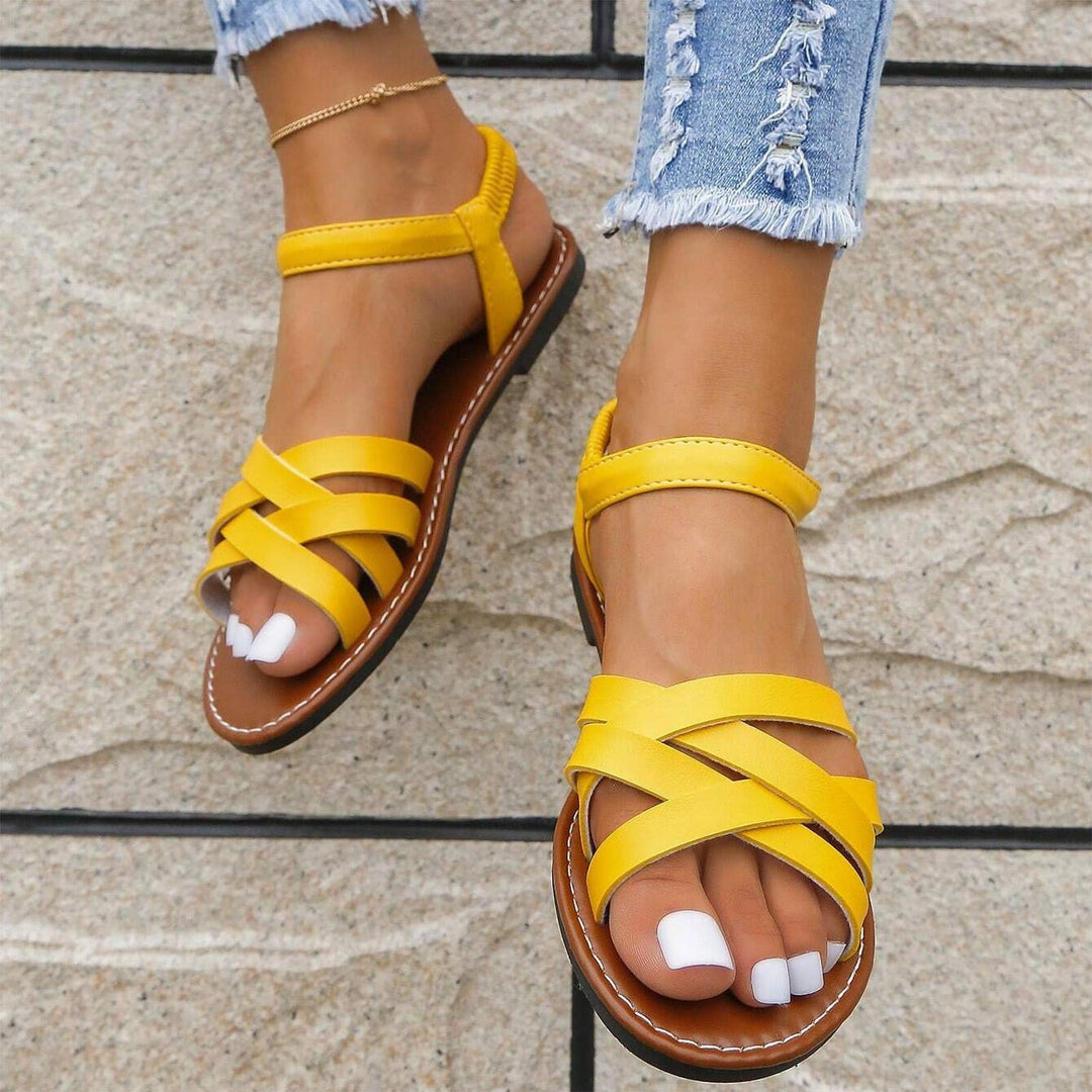 "Sandales plates femme à bandes croisées, couleur beige, idéales pour l'été, offrant confort et élégance pour la plage."