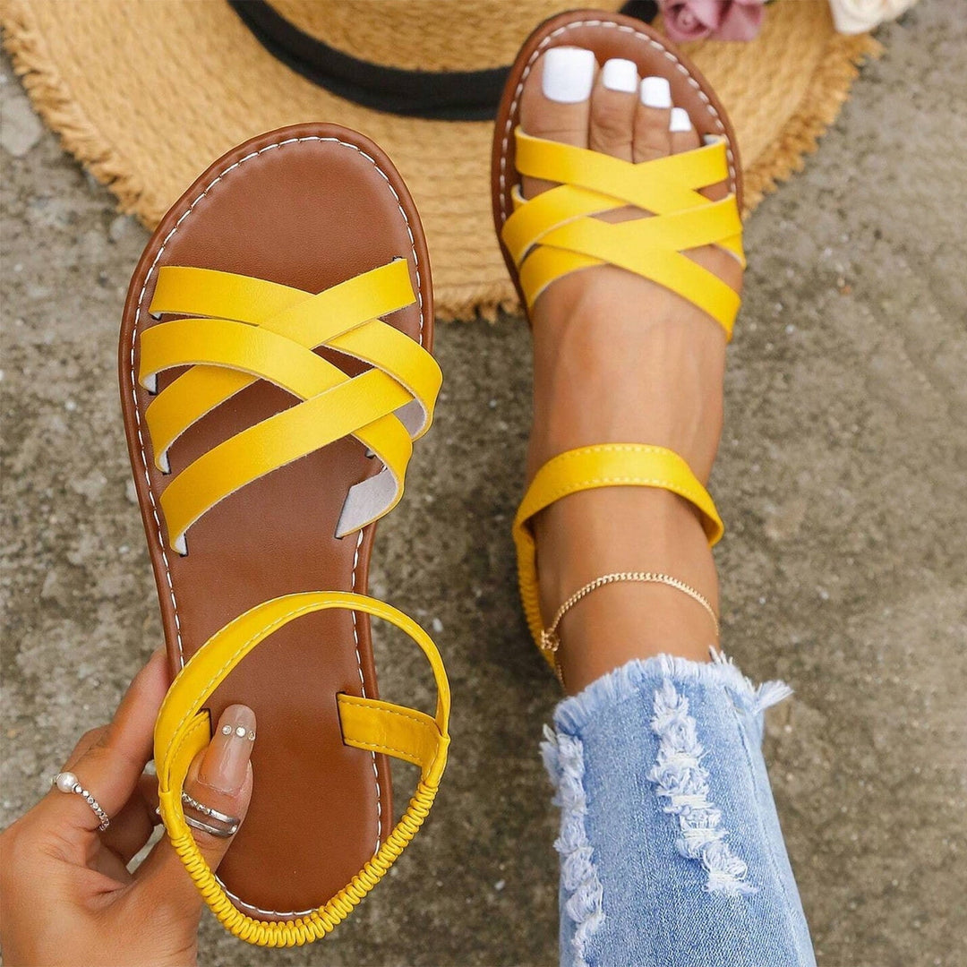 "Sandales plates femme à bandes croisées, couleur beige, idéales pour l'été, offrant confort et élégance pour la plage."