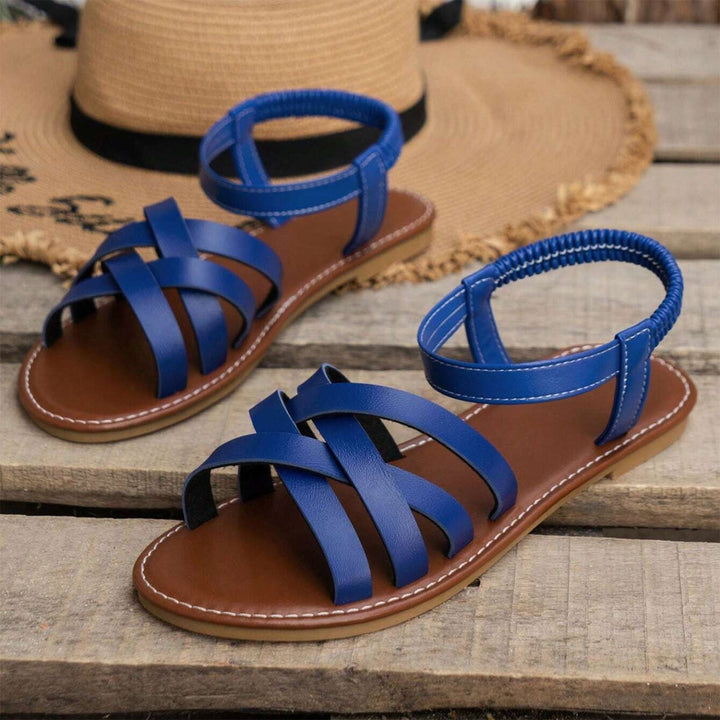 "Sandales plates femme à bandes croisées, couleur beige, idéales pour l'été, offrant confort et élégance pour la plage."
