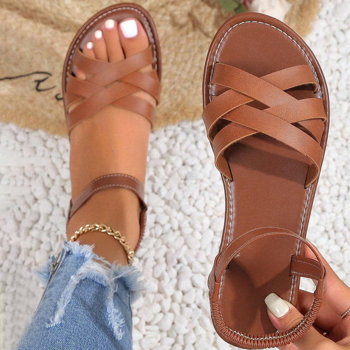 "Sandales plates femme à bandes croisées, couleur beige, idéales pour l'été, offrant confort et élégance pour la plage."