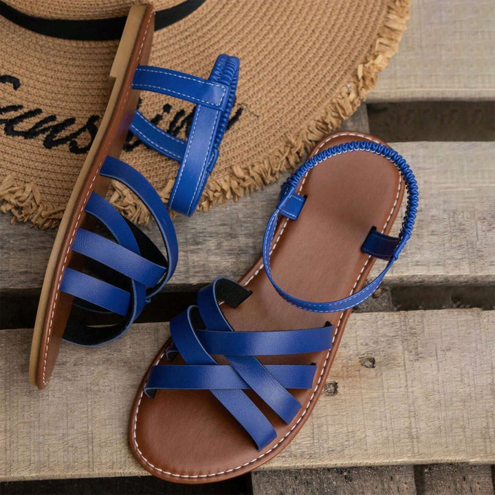 "Sandales plates femme à bandes croisées, couleur beige, idéales pour l'été, offrant confort et élégance pour la plage."