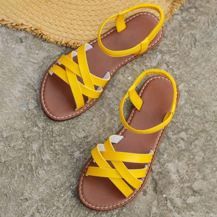 "Sandales plates femme à bandes croisées, couleur beige, idéales pour l'été, offrant confort et élégance pour la plage."