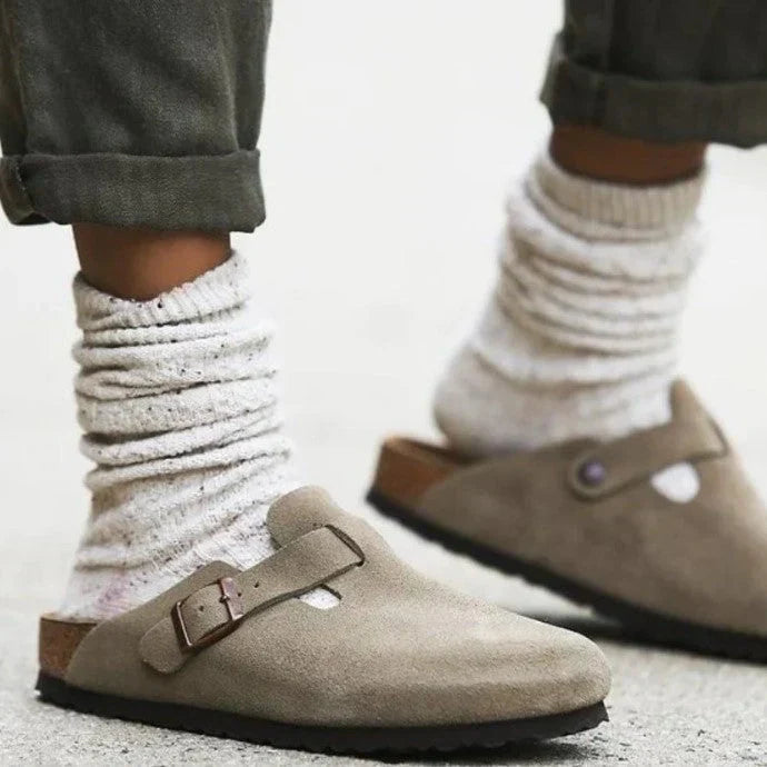 "Sandales unisexes élégantes en cuir beige sur fond de bois, style moderne et confort optimal."