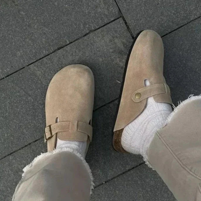 "Sandales unisexes élégantes en cuir beige sur fond de bois, style moderne et confort optimal."
