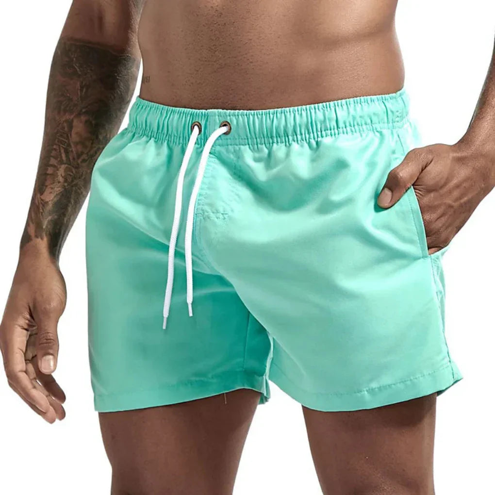 "Short de bain homme bleu clair, séchage rapide, doublure en mesh, poches latérales et arrière, ceinture élastique."