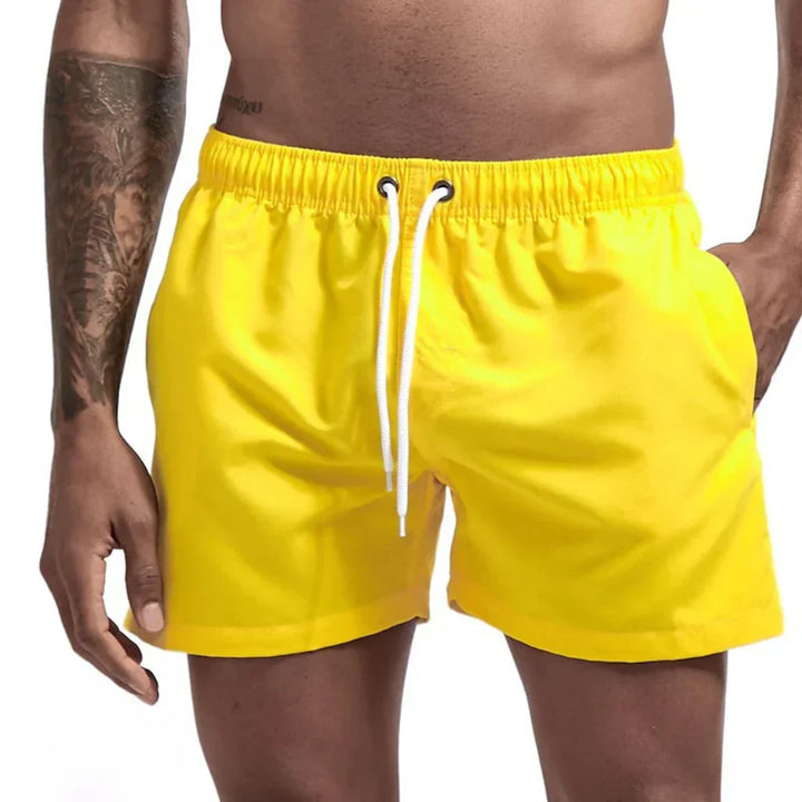 "Short de bain homme bleu clair, séchage rapide, doublure en mesh, poches latérales et arrière, ceinture élastique."