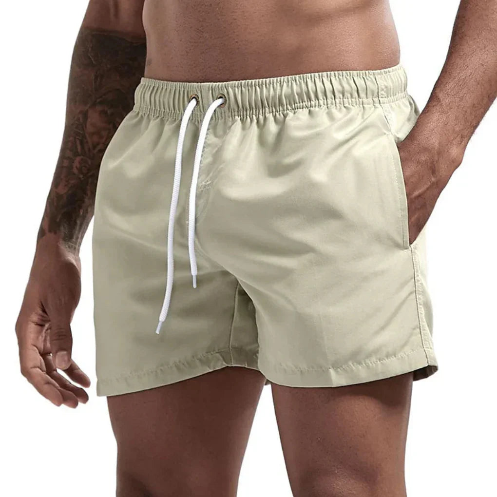 "Short de bain homme bleu clair, séchage rapide, doublure en mesh, poches latérales et arrière, ceinture élastique."